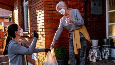 Volunteer bringing groceries to a senior woman at home during the coronavirus