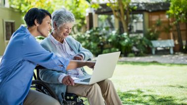 Long term care worker helping elderly woman.
