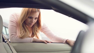 Woman inspecting a vehicle wondering how much a car really costs