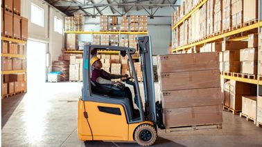Forklift loading inventory in a warehouse.