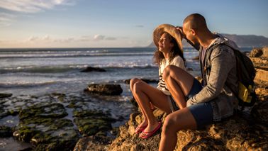 couple sitting on rocks by ocean