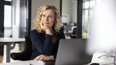 Woman thinking about the Northwestern Mutual quarterly market commentary she just finished reading.