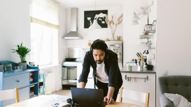 Manager looking at laptop during video conference call with remote workers