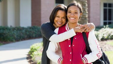 smiling mother hugging college-aged daughter